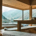 Warm wooden interior with mountain views through large glass windows creating a peaceful ambiance.
