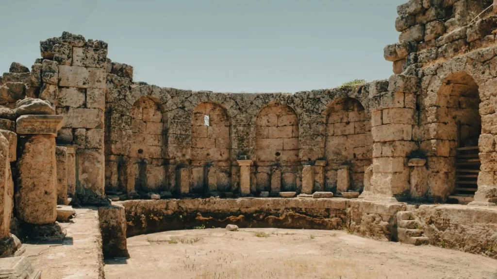 Ancient stone ruins feature historic arches and rugged landscape under clear sky.