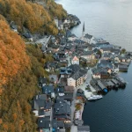 An aerial shot of Hallstatt, Austria surrounded by autumn foliage and lake views.