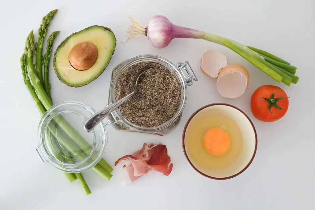 Flat lay of fresh asparagus, avocado, egg, tomato, and more for a keto-friendly dish.