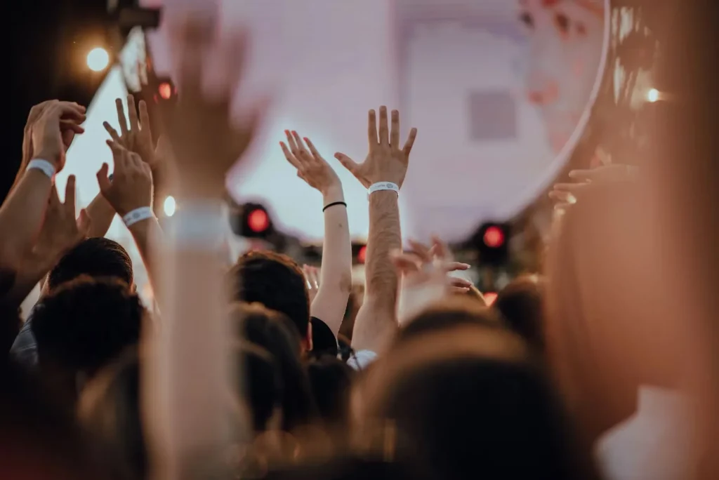 Vibrant scene of a thrilled audience with raised arms at an outdoor concert.