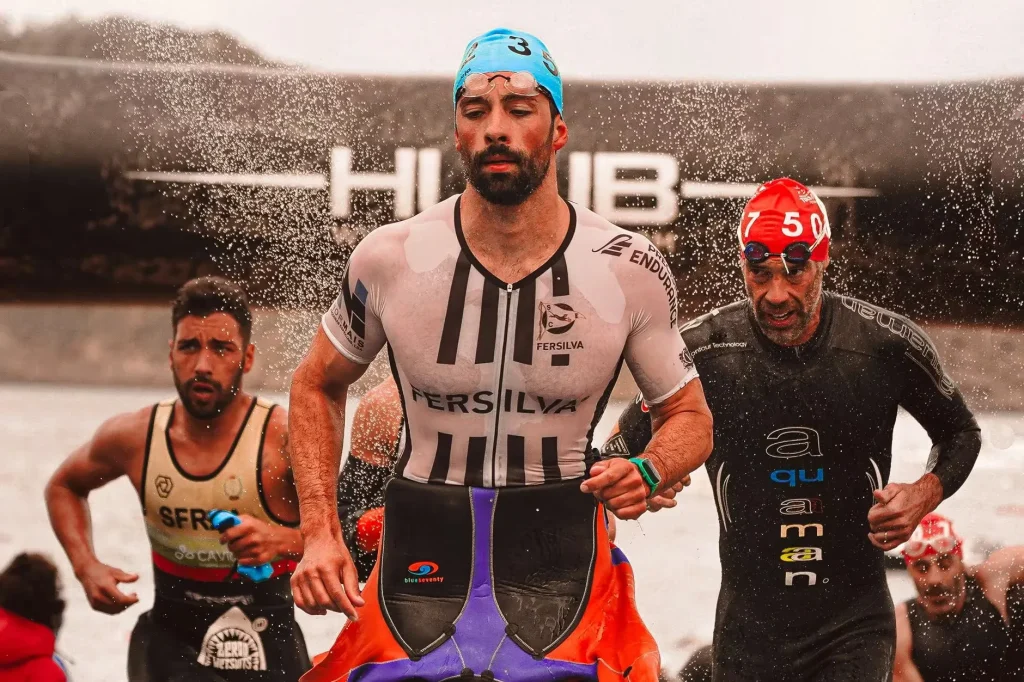 Runners sprinting through water during a competitive triathlon event outdoors.
