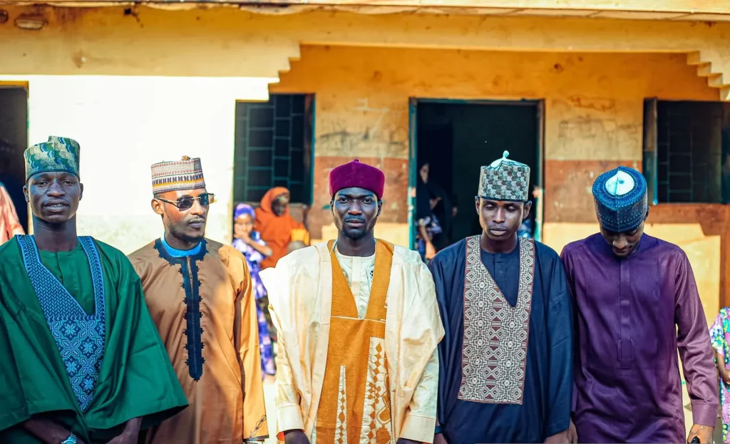 A group of men wearing traditional attire for a cultural gathering outdoors.