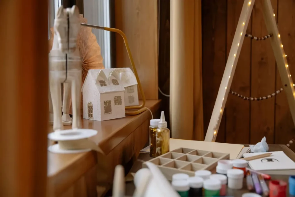 A warm and inviting arts and crafts station featuring Christmas decorations and materials on a wooden table.