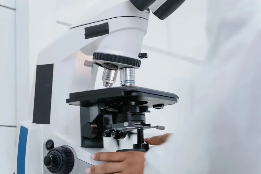 Detailed view of a scientist operating a microscope in a laboratory setting.